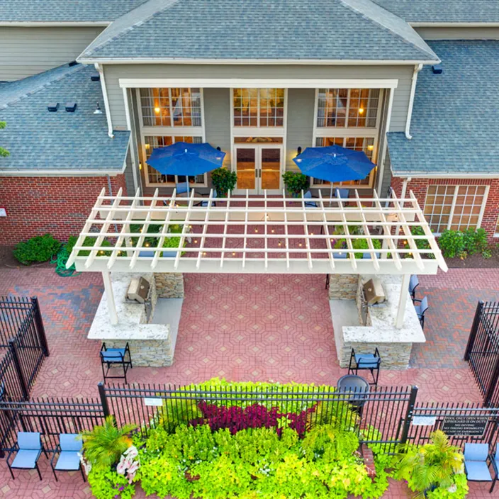 Spacious courtyard with pergola, lush greenery, and outdoor seating at Halstead Centreville apartments