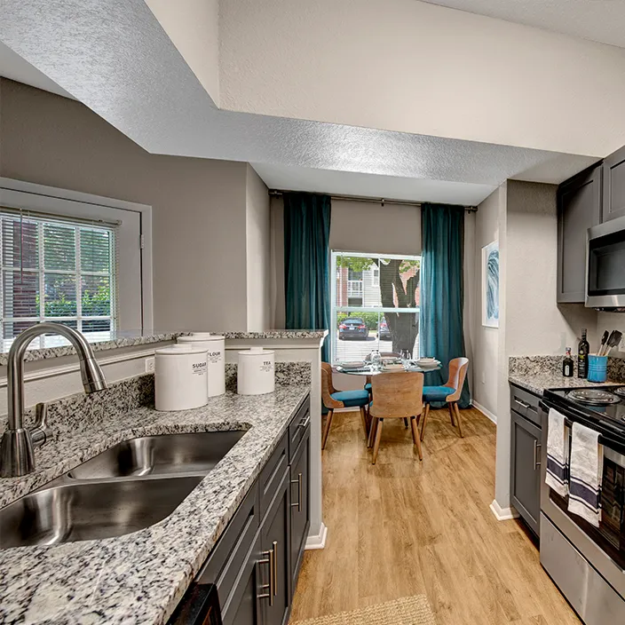 Granite-countertop kitchen with gray cabinets leading to a bright dining space at Halstead Centreville
