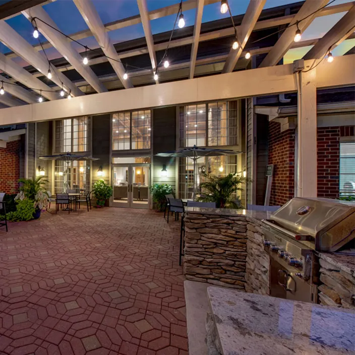 Charming outdoor patio with barbecue stations and pergola lighting at luxury Centreville apartments