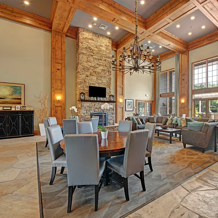 Spacious communal lounge with high ceilings, elegant chandelier, and expansive windows for natural light