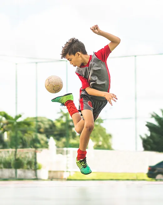 Young boy mid-air while playing soccer at Halstead Centreville’s sports court