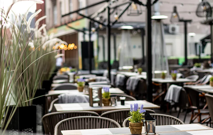 Stylish outdoor dining area at Halstead Centreville with small tables, plants, and overhead lighting
