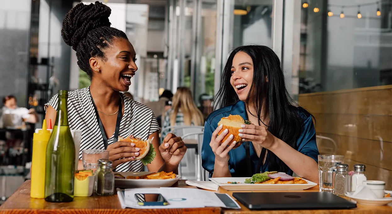 Friends laughing and enjoying a meal together at Halstead Centreville’s outdoor dining area