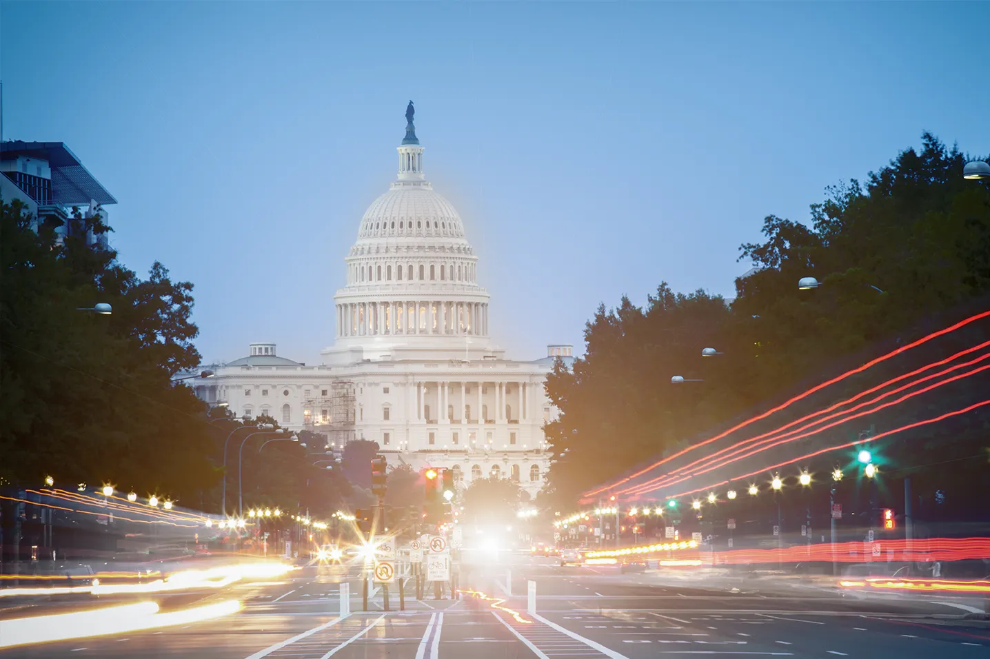 Iconic Washington, D.C. Capitol illuminated in the evening, with blurred city lights in the foreground