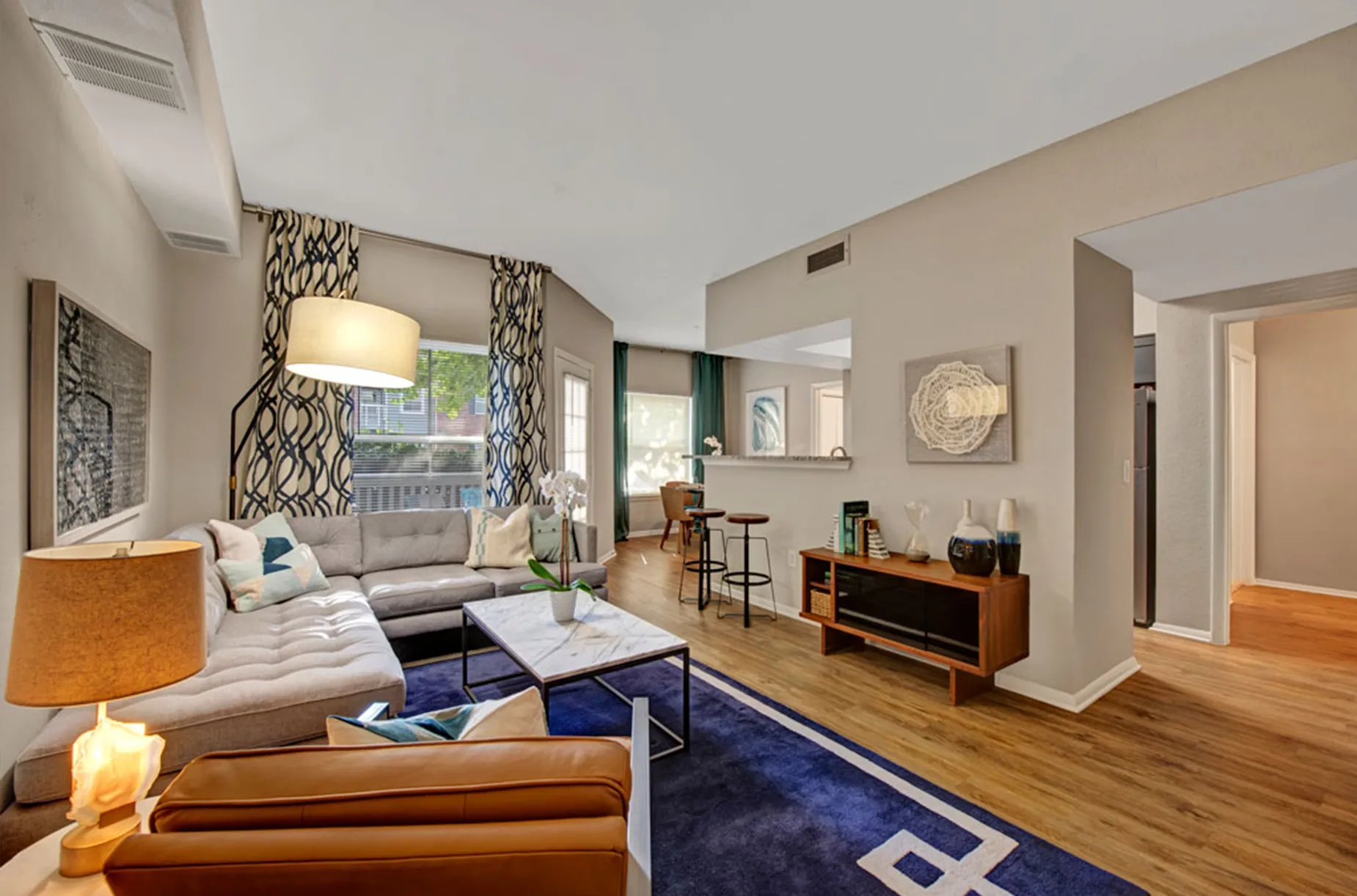 Spacious living area featuring a sectional sofa, wooden floors, and contemporary artwork on the walls