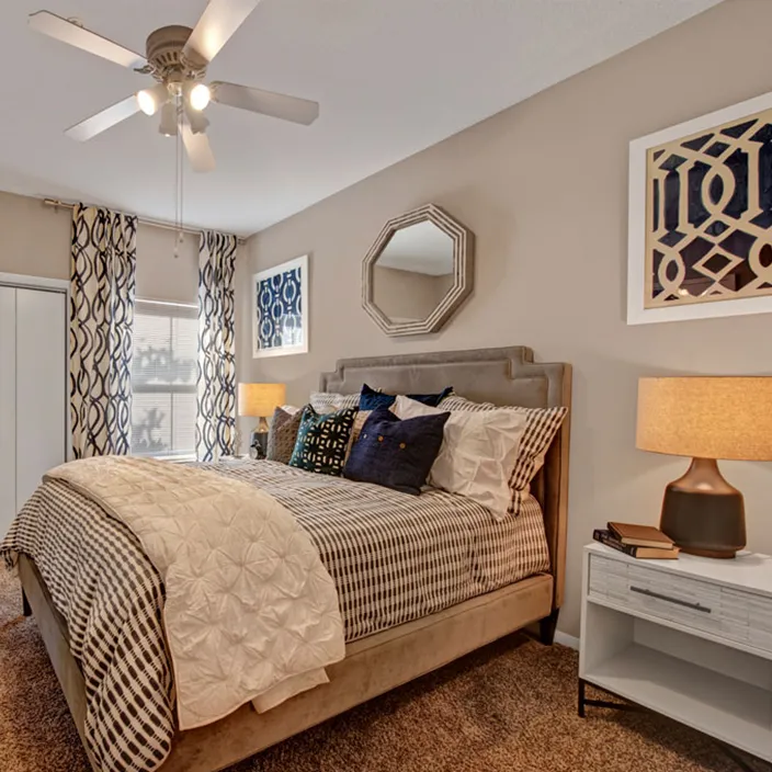 Contemporary bedroom with patterned pillows, stylish lamps, and neutral-toned decor elements.