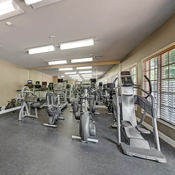 Fitness center featuring treadmills, ellipticals, and strength machines in well-lit workout space