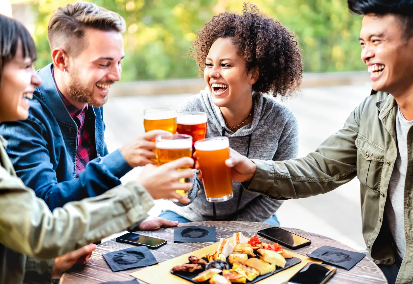 Group of friends toasting with drinks, sharing laughs at an outdoor social gathering